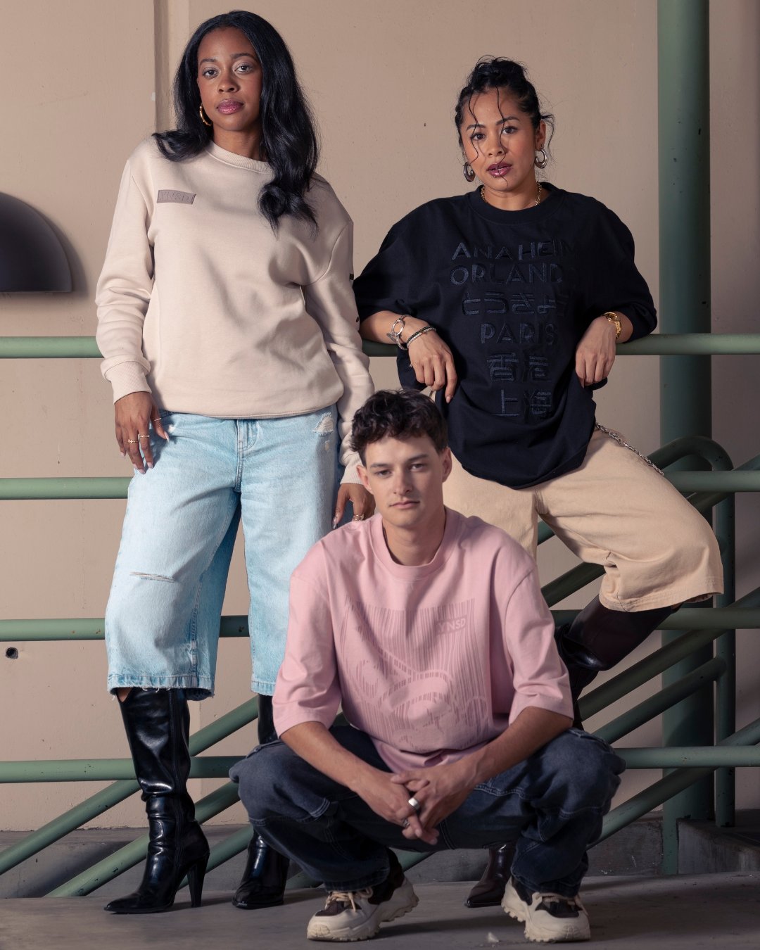 Three models wearing neutral Disney .YNSD shirts and sweatshirts