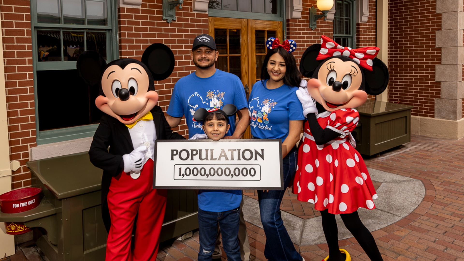 Andres Robles and his parents with Mickey Mouse, Minnie Mouse, and a Disneyland 1,000,000,000 population sign