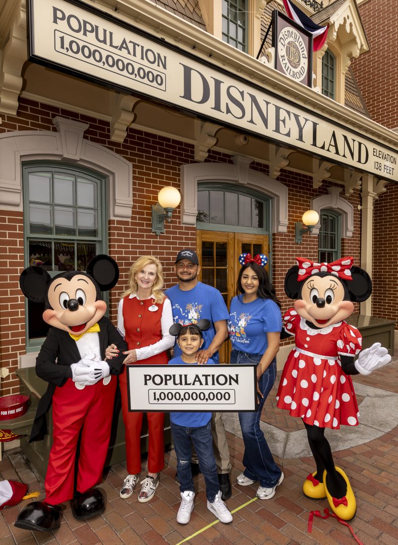 Jill Estorino with the Robles family, Mickey Mouse, Minnie Mouse, and the Disneyland 1,000,000,000 population sign