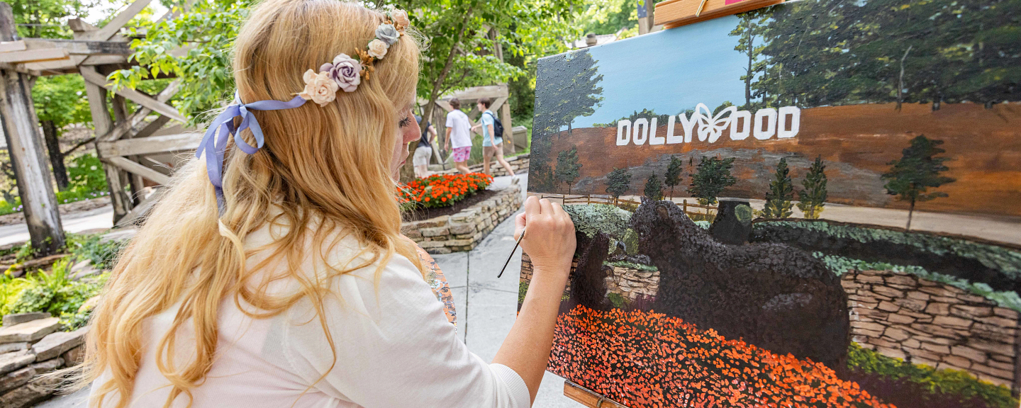 Artist Jaimie Houser paints a Dollywood entrance scene during the Flower and Food Festival