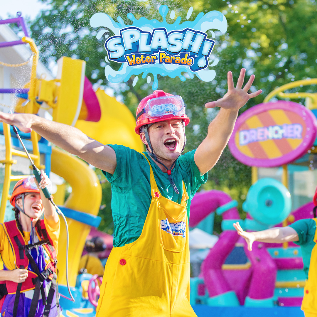 A SPLASH! Water Parade performer stands in front of a colorful water-spraying float