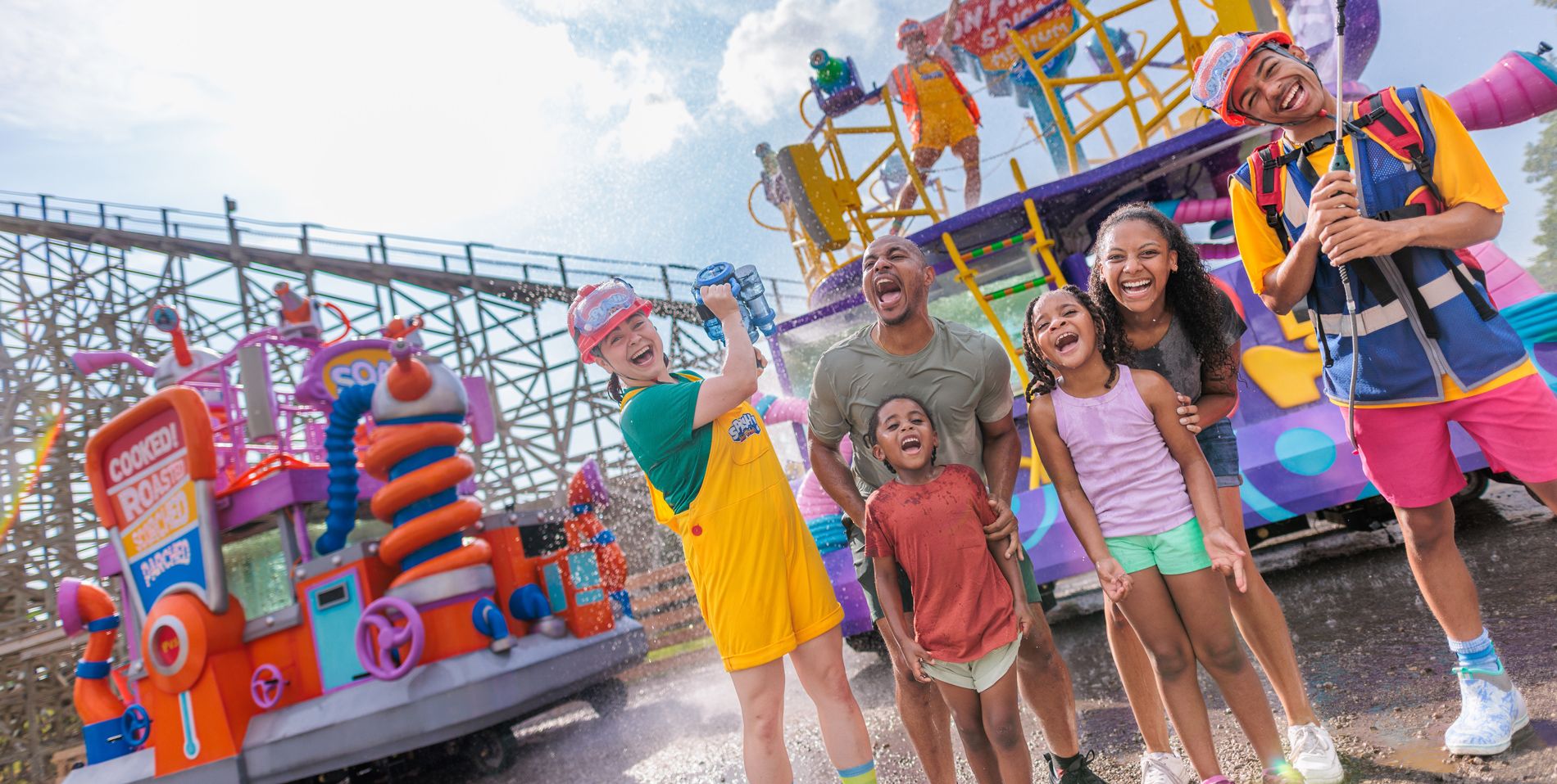 Families and SPLASH! Water Parade performers stand beside a water-spraying float at Dorney Park