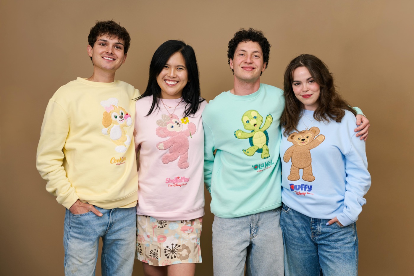 Four people model pastel Duffy and Friends sweatshirts in a Disney Parks preview