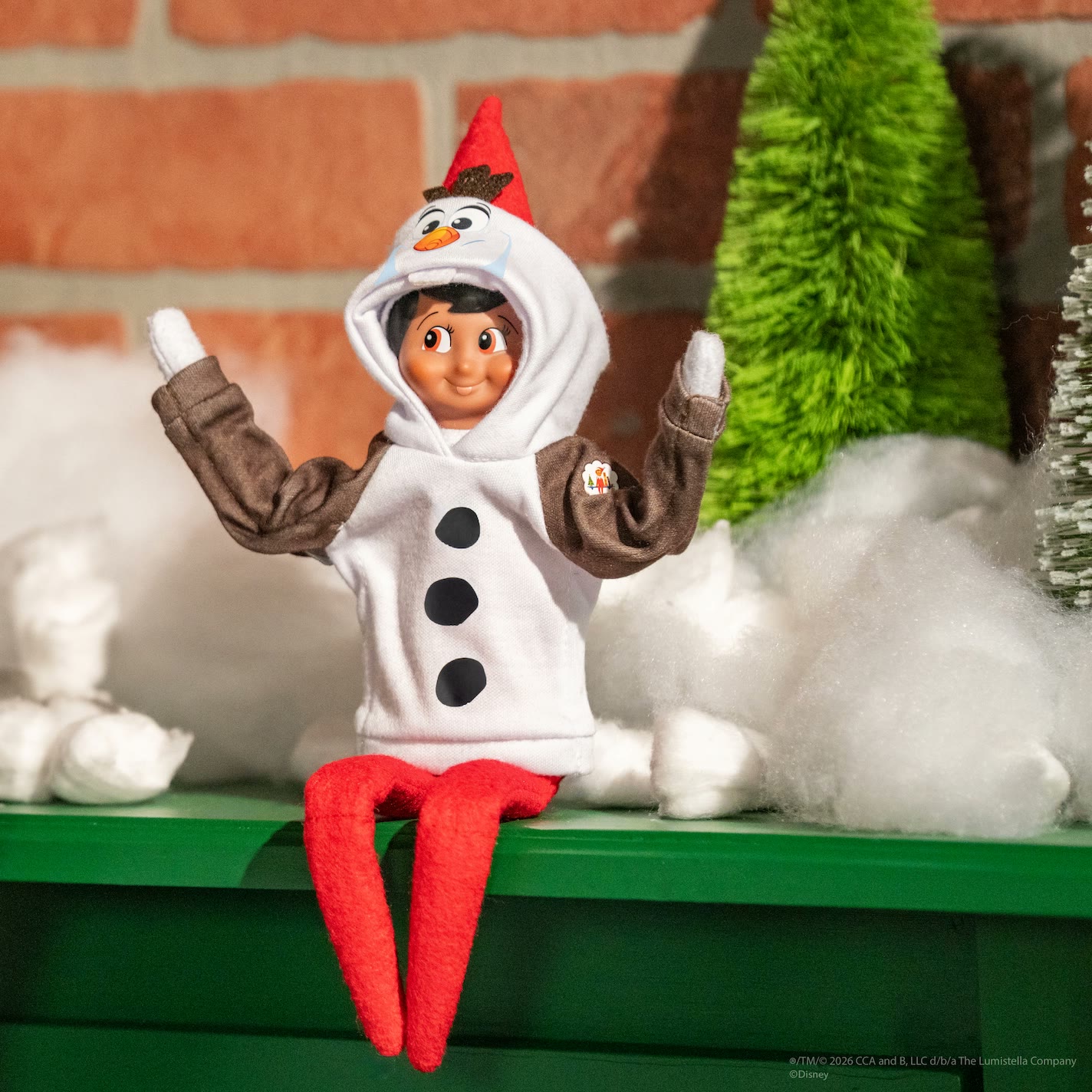 Elf on the Shelf wears an Olaf hoodie with a snowman face and twig-like hair
