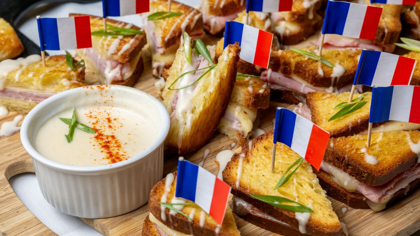 Miniature croque monsieur sandwiches with French flags and bechamel sauce