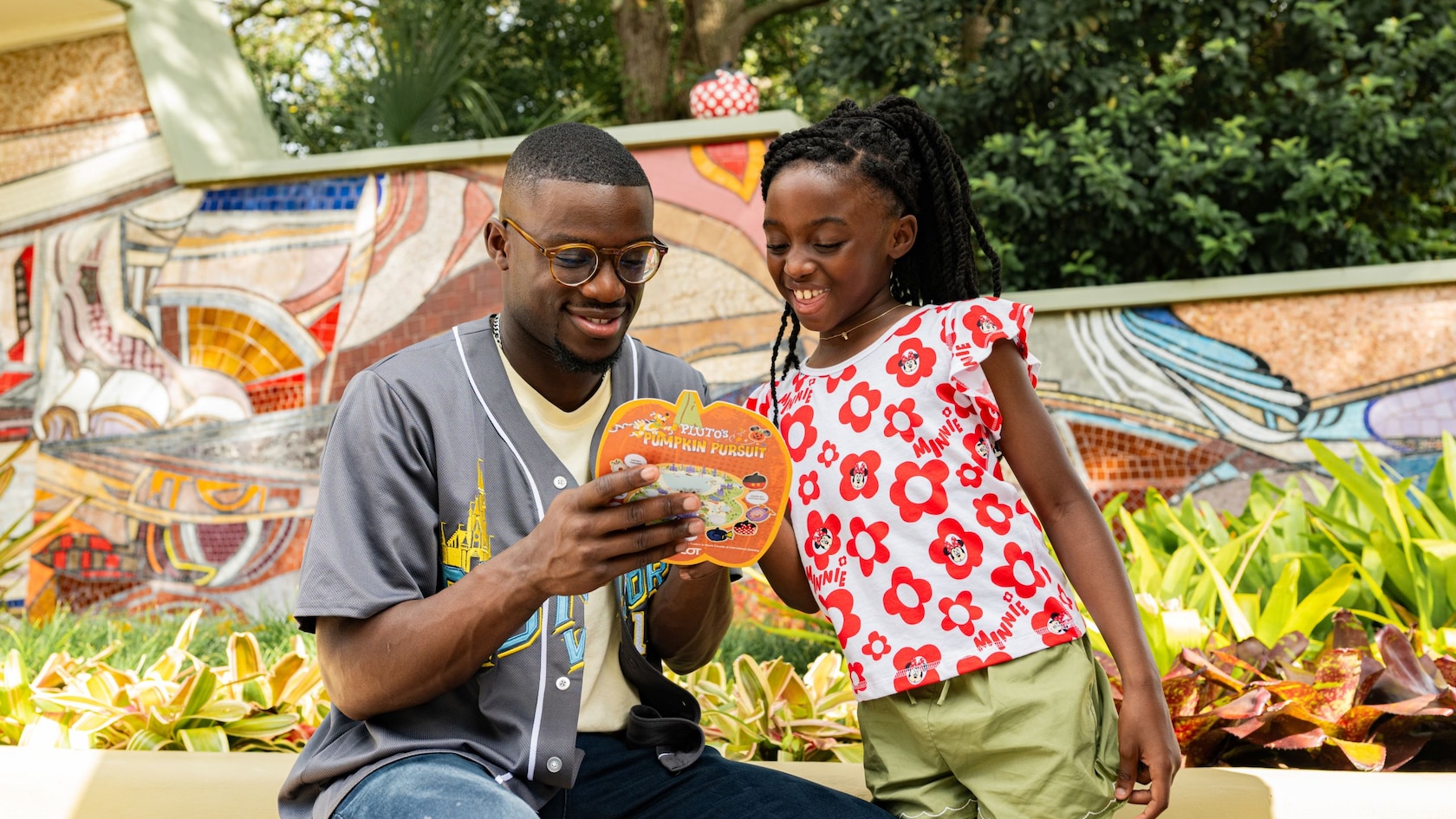 A father and daughter look at a Pluto’s Pumpkin Pursuit game board at EPCOT