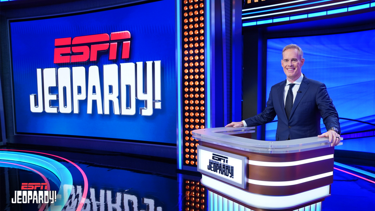 Joe Buck stands at the ESPN Jeopardy! host lectern