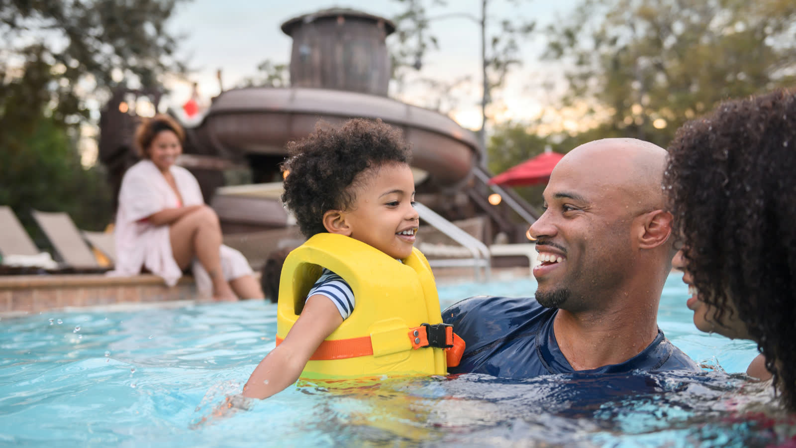 Family swimming at Disney's Fort Wilderness Resort with the pool slide behind them