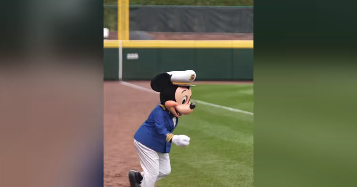 Captain Mickey Mouse in a Disney Cruise Line captain's hat runs across a baseball field