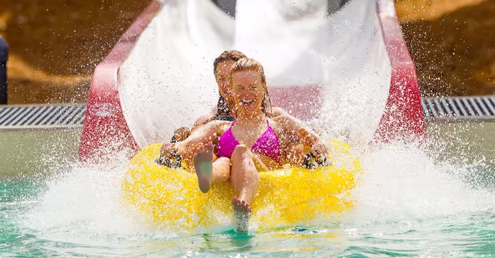Two guests ride a yellow tube down a Carolina Harbor water slide