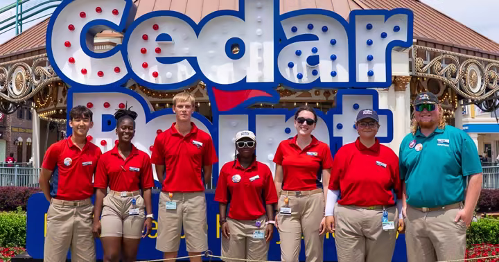 Seven Cedar Point ride operations team members in front of the Cedar Point sign