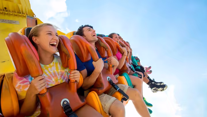Riders secured in orange over-the-shoulder restraints on a Cedar Point pendulum ride