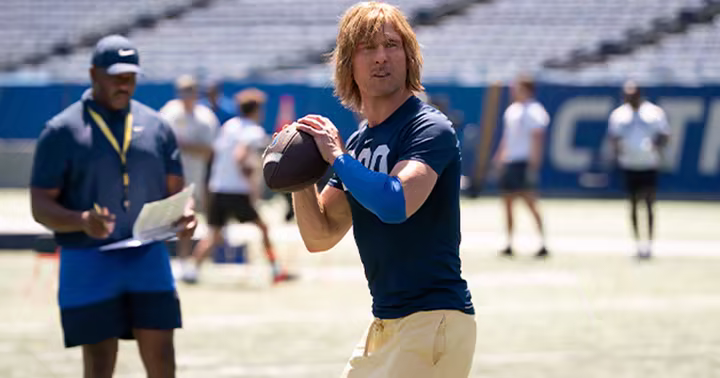 Glen Powell as Chad Powers stands on a football practice field