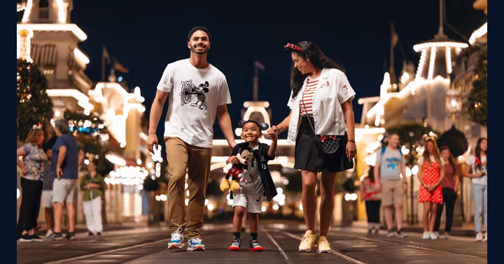 A family walks along Main Street, U.S.A. at Magic Kingdom after dark