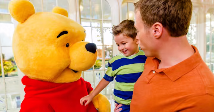 Winnie the Pooh meets a family inside The Crystal Palace at Magic Kingdom