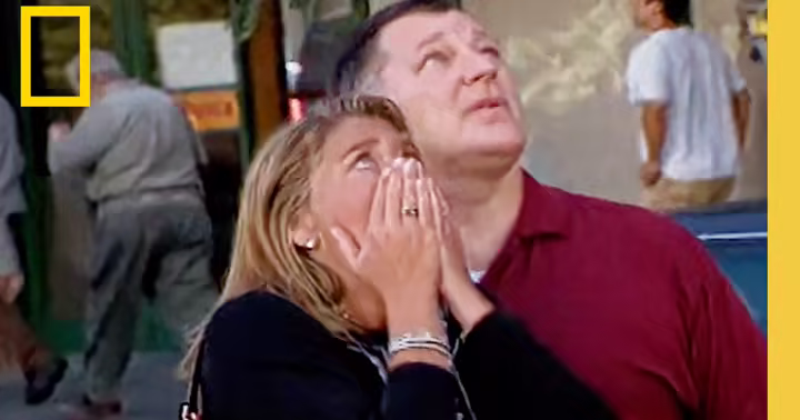 Two people look upward in a National Geographic 9/11 Reunited trailer still