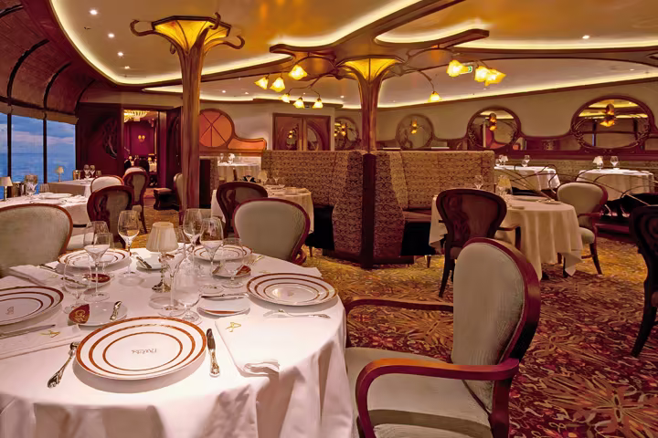 The Remy dining room aboard a Disney Cruise Line ship, set with glassware and white tablecloths