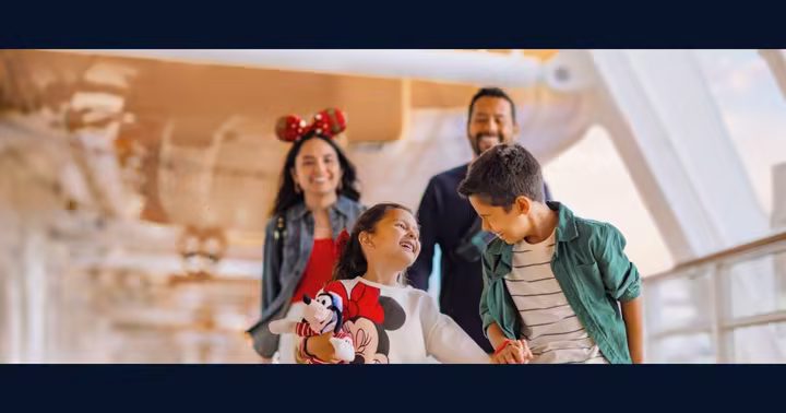 A smiling family walks together on the deck of a Disney Cruise Line ship