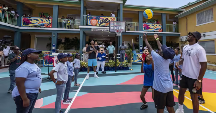 Students play basketball with Mickey Mouse and Buddy Hield at Woodcock Primary School