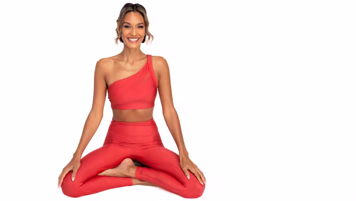 Peloton instructor Aditi Shah seated in a Pilates pose against a white background
