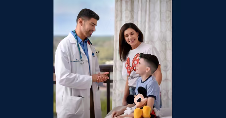 An AdventHealth physician speaks with a mother and child during a Disney World Resort hotel room visit