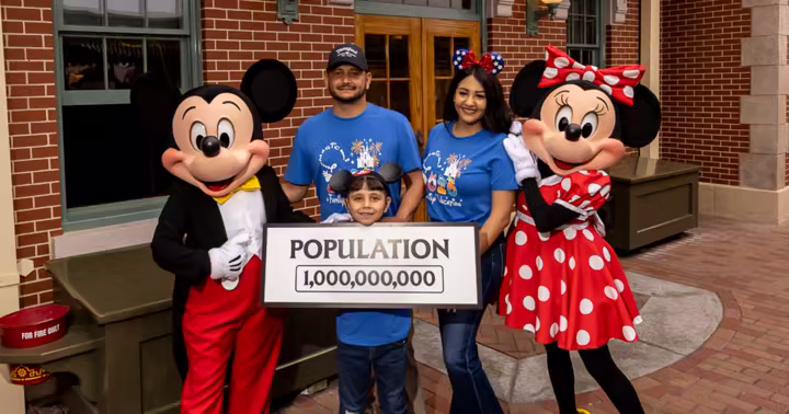 Andres Robles and his parents with Mickey Mouse, Minnie Mouse, and a Disneyland 1,000,000,000 population sign