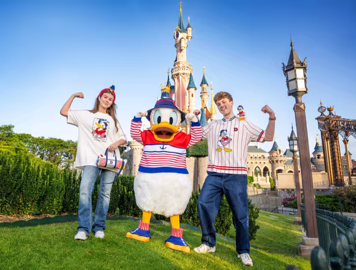Donald Duck in a nautical outfit with matching Disneyland Paris merchandise in front of Sleeping Beauty Castle