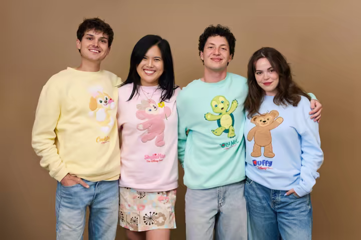 Four people model pastel Duffy and Friends sweatshirts in a Disney Parks preview