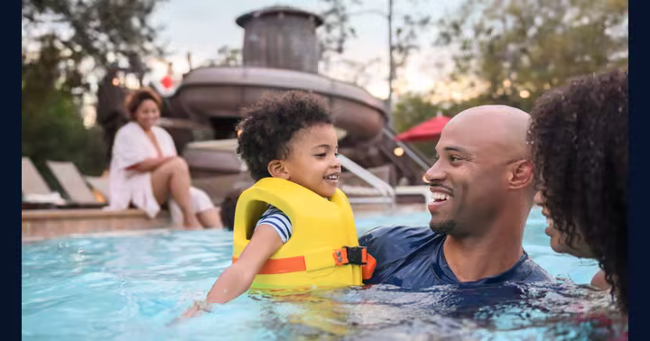 Family swimming at Disney's Fort Wilderness Resort with the pool slide behind them