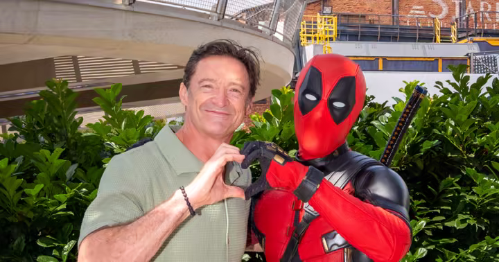 Hugh Jackman and Deadpool form a heart with their hands at Marvel Avengers Campus
