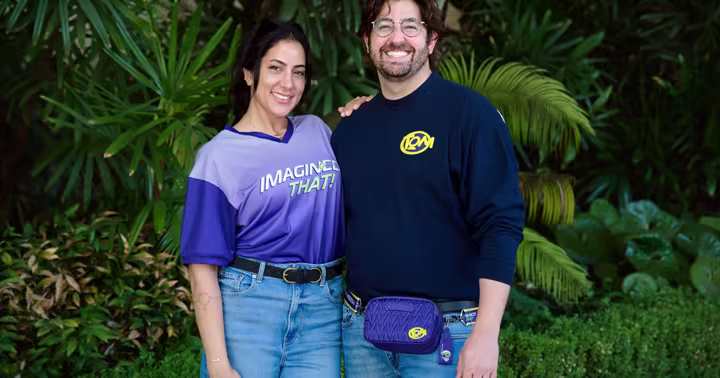Two models wearing shirts from the Imagineer That collection for D23 2026