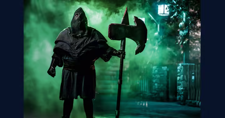 Hooded Knott's Scary Farm performer holding an axe in green fog