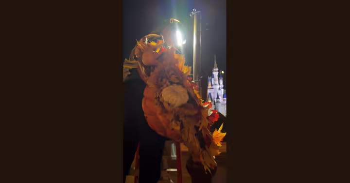 A cast member installs a Mickey pumpkin wreath at Magic Kingdom