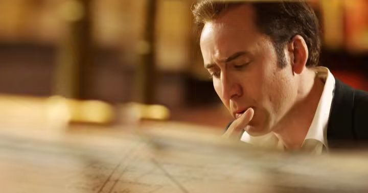 Nicolas Cage as Benjamin Franklin Gates studying a map in National Treasure