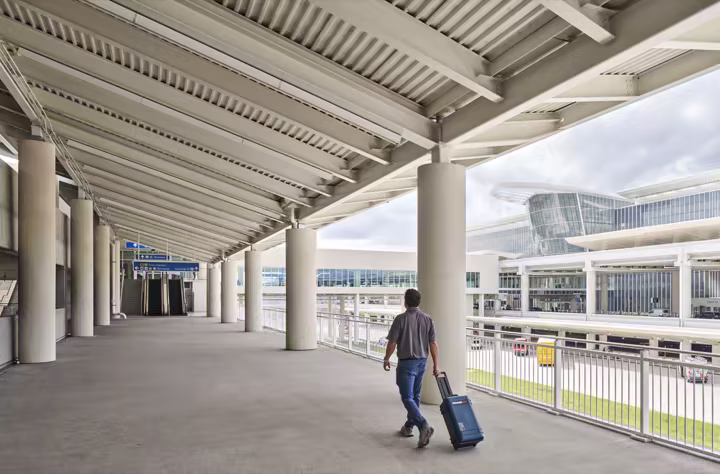 A traveler with luggage outside Terminal C at Orlando International Airport