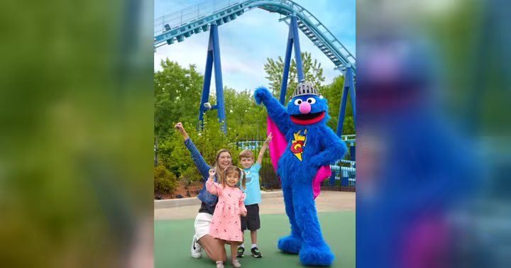 Grover poses with a family near a roller coaster at Sesame Place Philadelphia