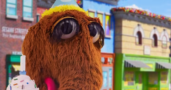 Snuffy wears a birthday hat and holds a cupcake at Sesame Place Philadelphia