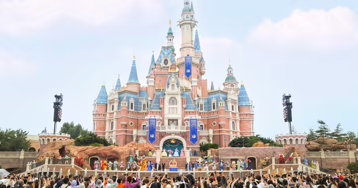 Disney characters and performers gather around Shanghai Disney Resort's 10th birthday cake in front of Enchanted Storybook Castle