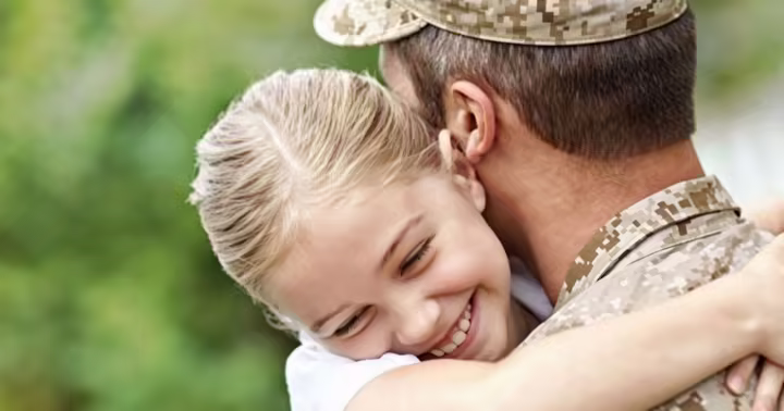 A military member hugging his daughter at a Six Flags park