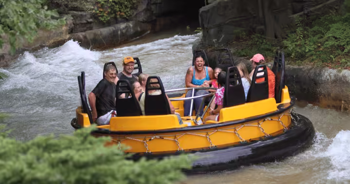 A yellow Roaring Rapids raft carrying guests through the water at Six Flags Great America