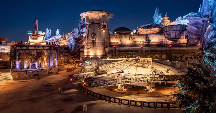 The Millennium Falcon parked outside Ohnaka Transport Solutions at night in Star Wars: Galaxy's Edge