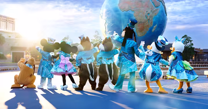 Mickey Mouse and friends in blue anniversary costumes facing the Aquasphere at Tokyo DisneySea