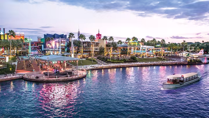 Universal CityWalk at dusk, viewed across the lagoon with a water taxi in the foreground
