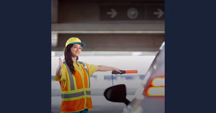 A Universal Orlando parking team member directs a car inside a resort garage