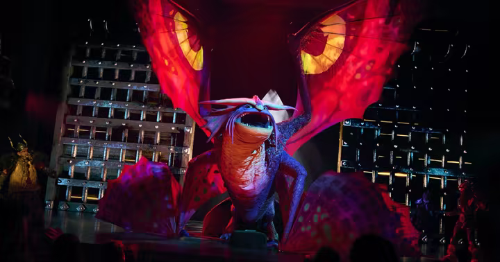 A large dragon puppet performs in The Untrainable Dragon at Epic Universe