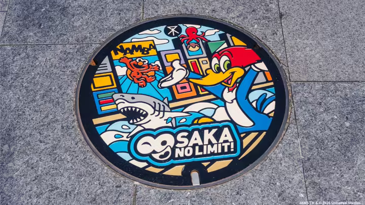 Universal Studios Japan 25th anniversary manhole cover with Woody Woodpecker, Jaws, and Osaka artwork