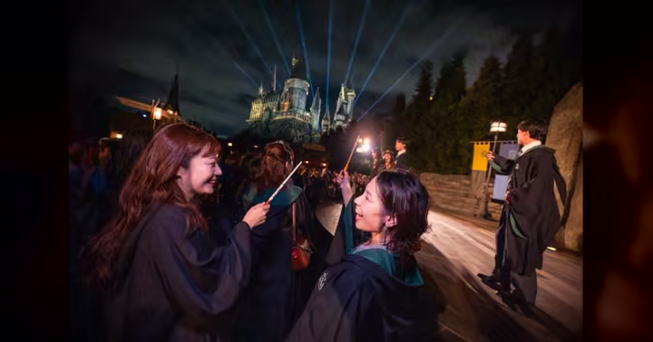 Guests raise wands as Hogwarts Castle glows during Universal Studios Japan's Back to Hogwarts event