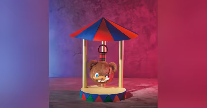 HamiKuma face keychain displayed beneath a striped carnival canopy