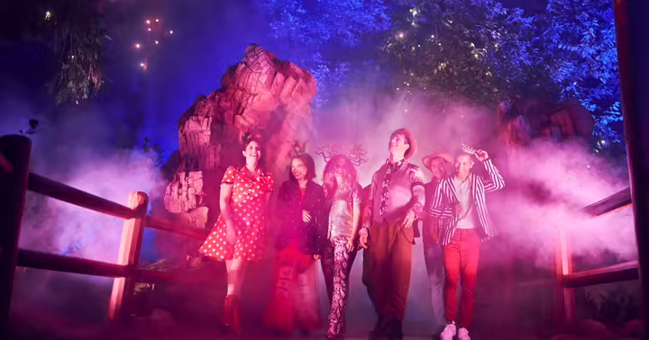 Guests walk through the mist and colored light of Villains Grove at Disney California Adventure