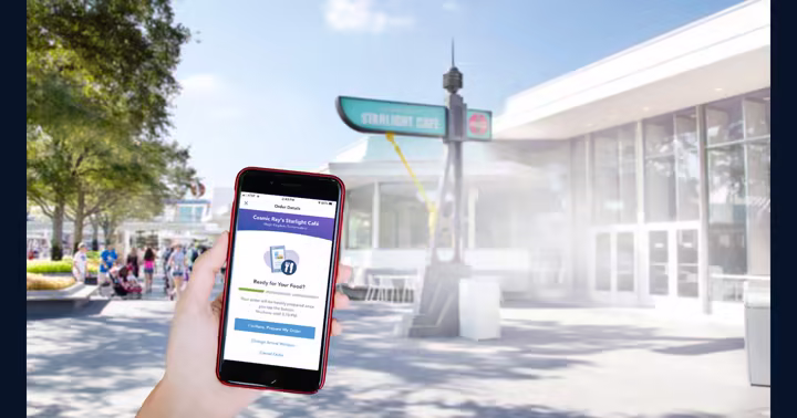 A Walt Disney World guest uses Mobile Order on a phone in front of Cosmic Ray's Starlight Cafe